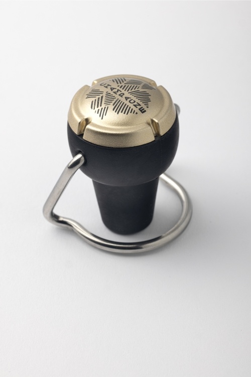 Bouchon hermétique en caoutchouc noir et or avec un marquage du mot Champagne